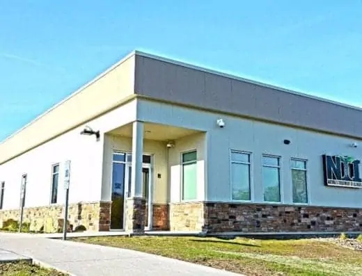 Front of a building with a sign advertising Nature's Treatment of Illinois, a dispensary near Milan, Illinois.