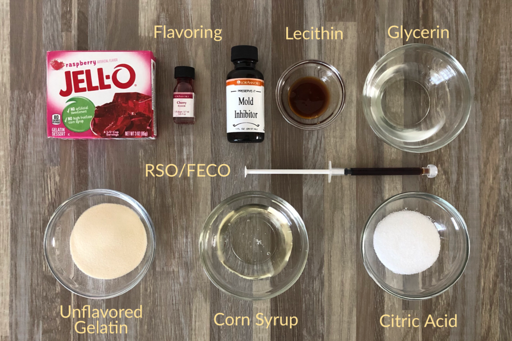 Ingredients needed to Make The Best Sour Gummy Bears Infused With Cannabis.
on a table are both flavored and unflavored Jello, extra candy flavoring, mold inhibitor, lecithin, glycerin, corn syrup, citric acid, and RSO/FECO.