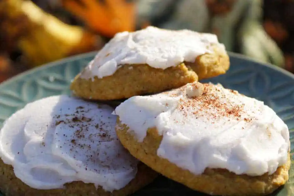 A plate full of frosted cannabis infused pumpkin cookies with cinnamon dusted on top.