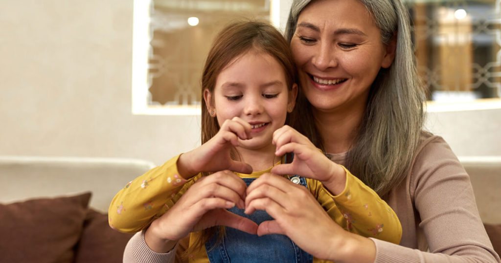 A medical marijuana caregiver plays with a child patient by making heart shapes with her hands. 