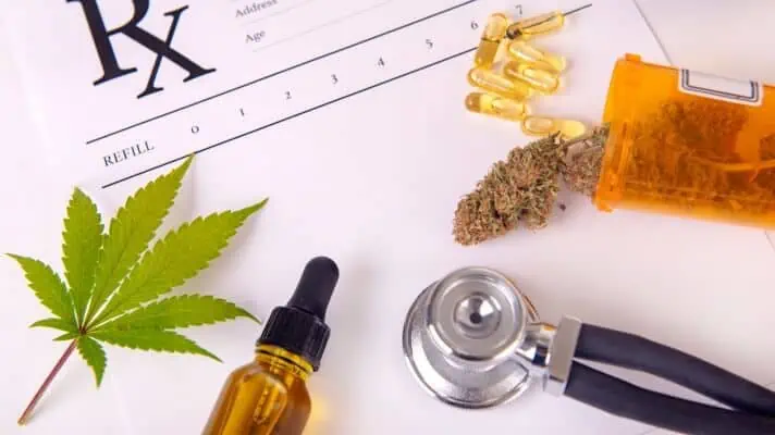 An RX paper sits with a green cannabis leaf, cannabis oil, a stethoscope and medical marijuana on top. 