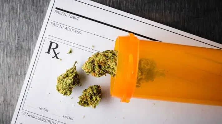 Certified Medical cannabis pored out from an orange pharmacy pill bottle onto a prescription pad. 