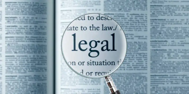 This photo shows a magnifying glass zooming in on a dictionary, specifically on the word "legal".
