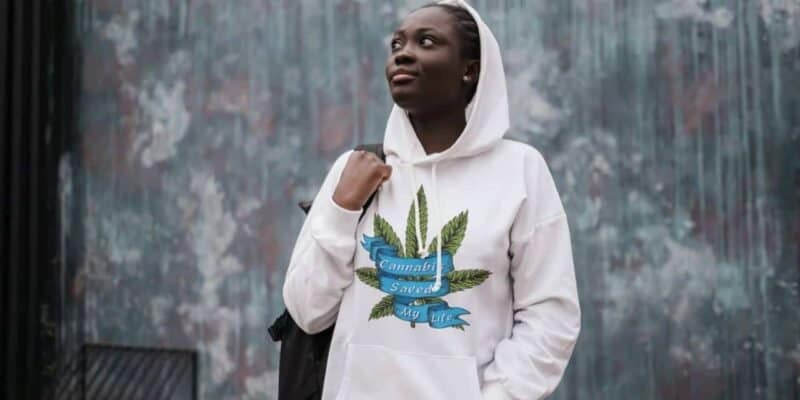 Created by The Cannabis Community, this photo shows a woman wearing a white hoodie that reads "cannabis saved my life"
