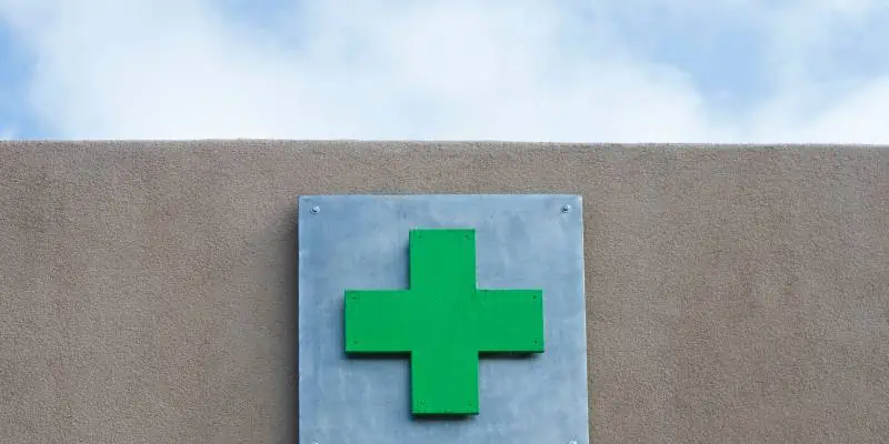 This image shows a green cross sign on the top of a concrete building.