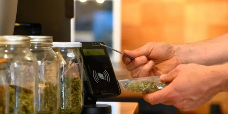 This photo shows a customer processing a transaction with a debit card at a point of sale system to buy cannabis.