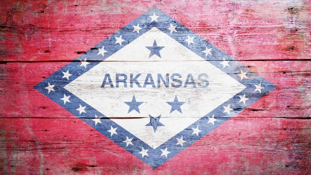 Talking about Arkansas gun rights for medical cannnabis patients, the image features the state flag painted across a rustic looking wooden background