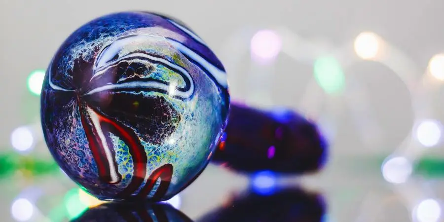 A luminescent aqua blue bowl with a close up focus is featured against a blurred background and lighting effects, highlighting the design and style of american glass