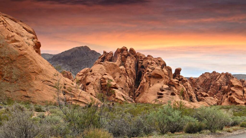 Discussing the important topic of cannabis gun rights in Nevada for medical cannabis patients, this image features a background of the Nevada desert mountains in the late evening sky as the sun sets.