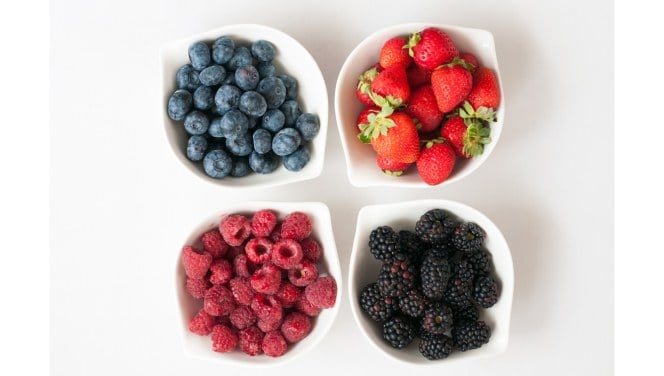 Four bowls of low-sugar berries on a white background.