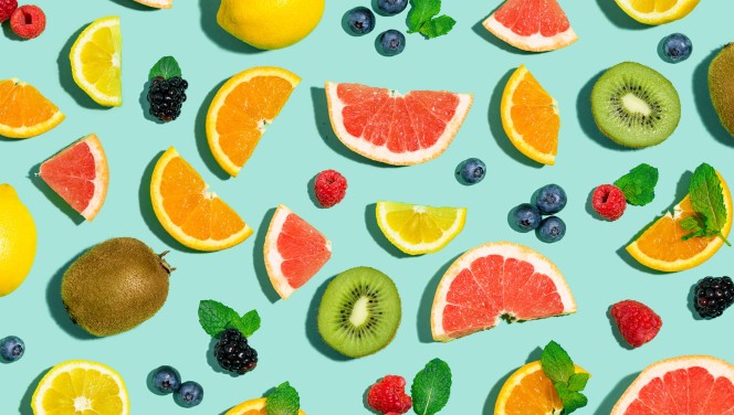 A variety of fruits are shown on a blue background, featuring cannabis-infused gummies.