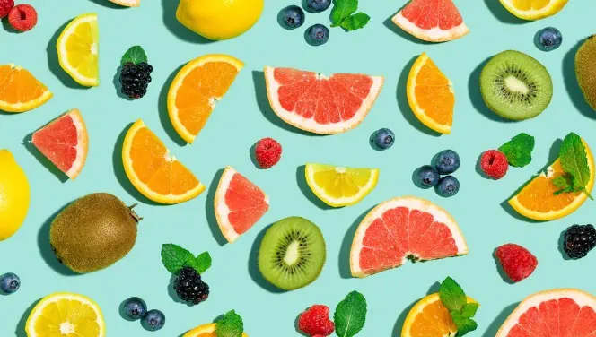 A variety of fruits are shown on a blue background, featuring cannabis-infused gummies.