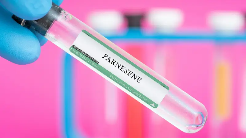 A test tube labled Farnesene is shown with bright pink background.