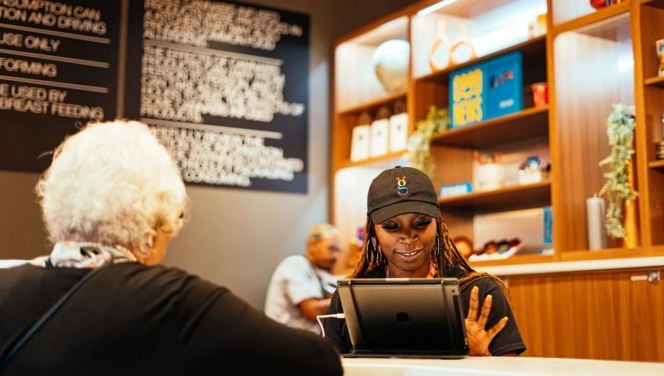 Grasshopper Club Chicago in Logan Square is a Chicago Dispensary ready to help you. A young woman concierges helps a customer. 