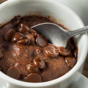 A tasty chocolate cannabis infused mug cake with a silver spoon and chocolate chips