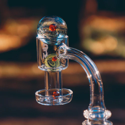 Close-up of a transparent glass bong with intricate details, featuring a swirling design inside a clear bubble.