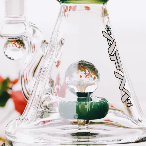 Close-up of a glass water pipe with intricate details and a clear sphere, against a soft-focus background.