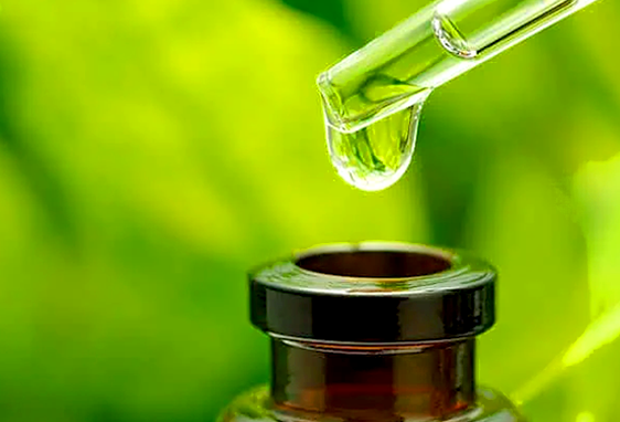 A close-up of a glass dropper releasing a droplet into a small brown bottle, set against a blurred green background—evoking Urban Farmacy’s natural cannabis delivery offerings in Portland, Oregon.